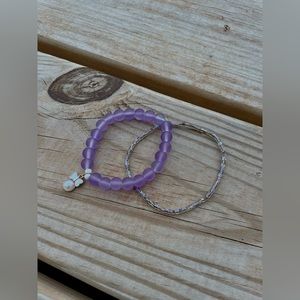 Two beaded bracelets, one with a charm. Both purple and same size